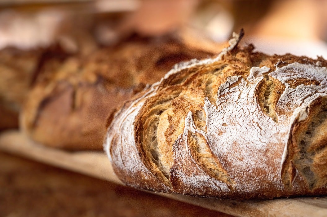 Sauerteigbrot mit knuspriger Kruste auf einem Holzregal. 